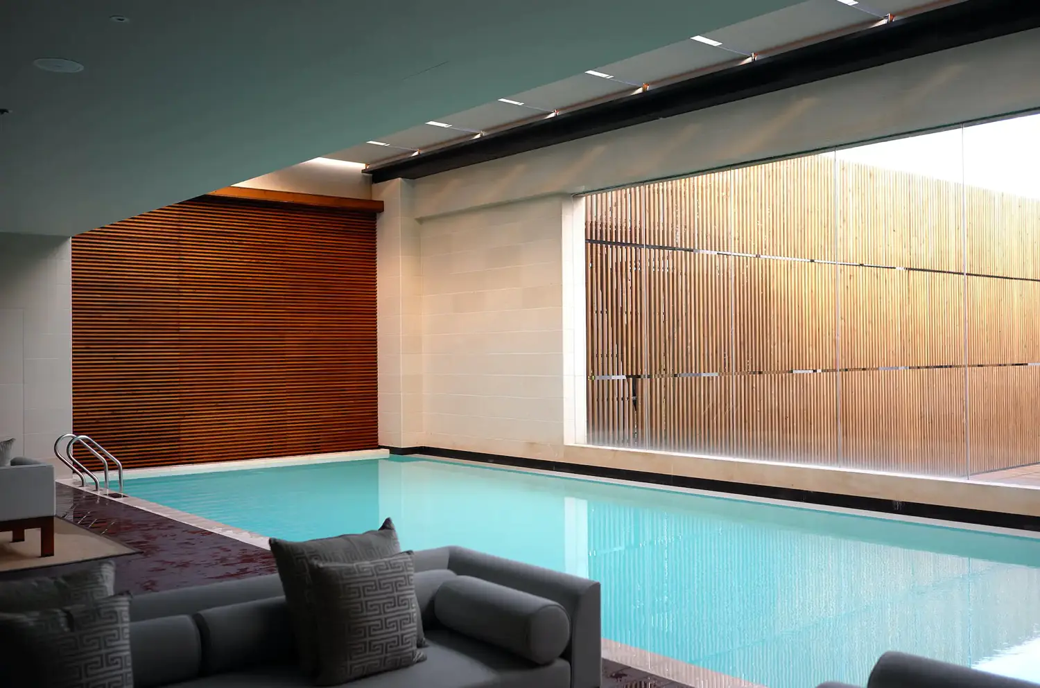 Indulge in The Luxury List's New York City serene indoor pool sanctuary, featuring a modern design with sleek lines and a tranquil aqua reflection.