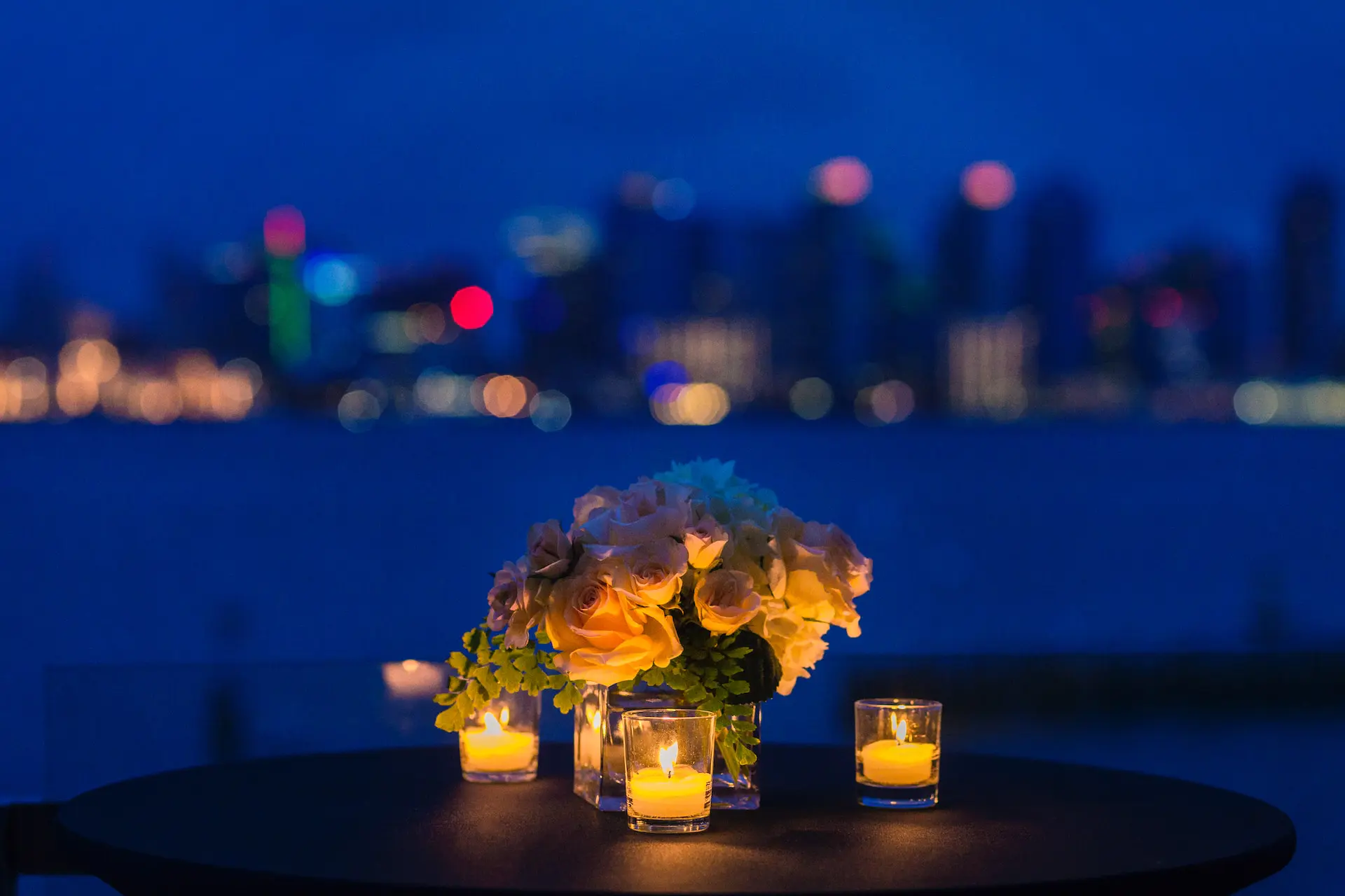 Exclusive Waterfront Dining: Indulge in a luxurious dining experience by The Luxury List, with an elegant table set against the New York City night skyline, enhancing romantic evenings.